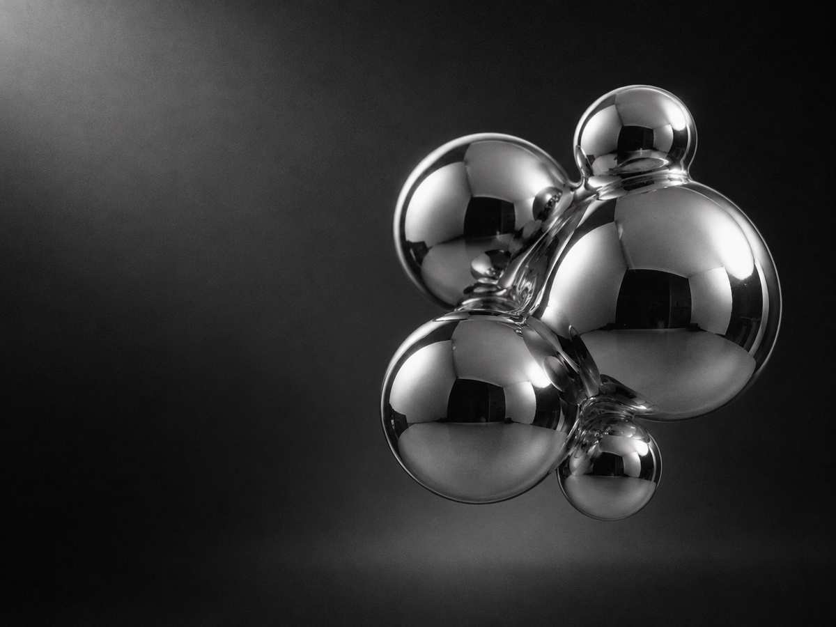 Black and white 3D render of fused chrome spheres under soft studio light