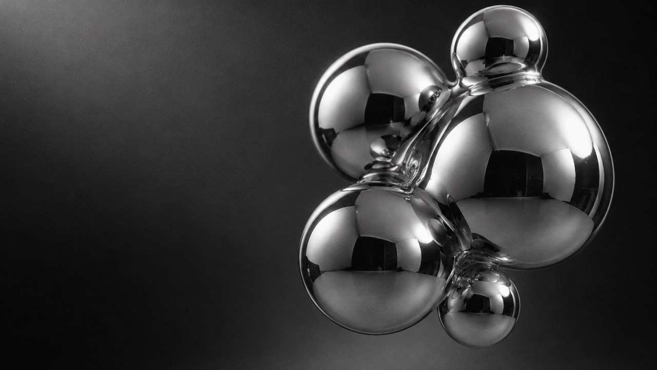 Black and white 3D render of fused chrome spheres under soft studio light